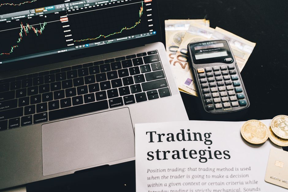 Close-up image of a trading setup with a laptop, calculator, and financial documents
